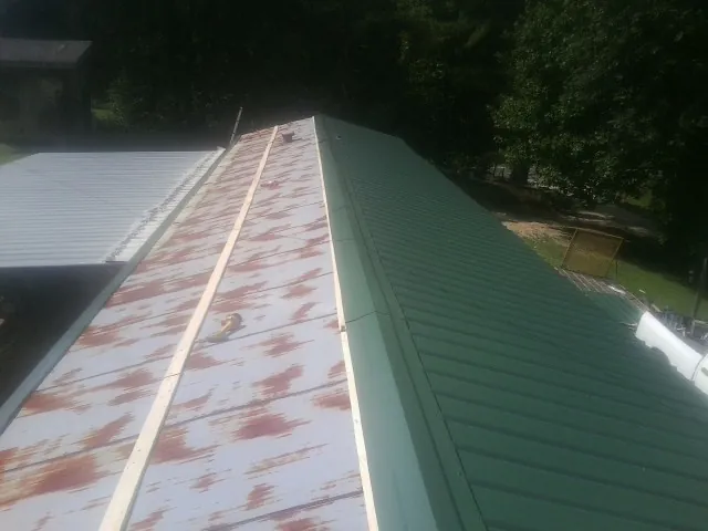 Old rusted panels beside newly installed green metal roofing — Wind Damage Roof Repair by Roofing Brothers in Grahamsville
