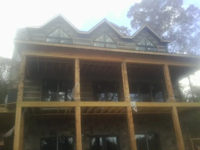 Dormers and porch framing on a large log home under construction — Roof Coating work by our crew in Grahamsville