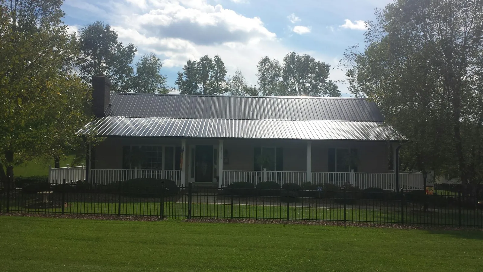 Gray metal roof on a brick ranch with a full width front porch — Gutter Guard Installation work by our crew in Grahamsville