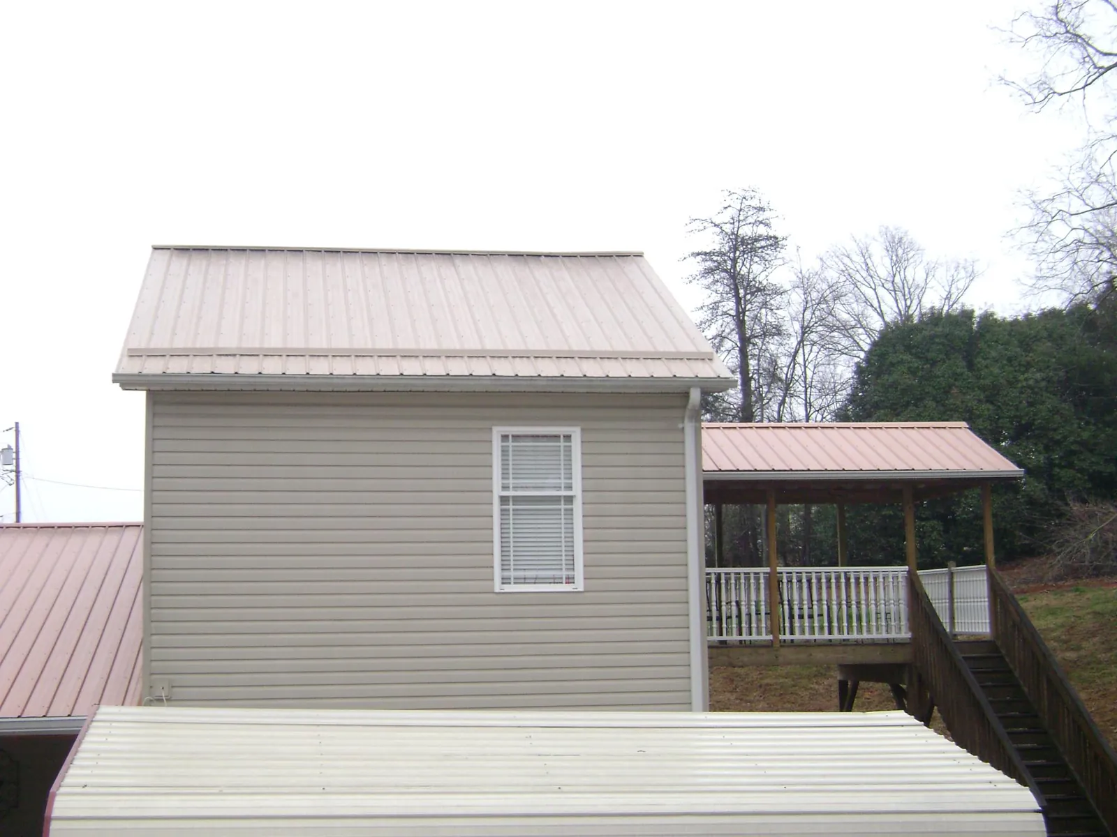 Tan metal roofs on a two story addition and attached porch, from a Roof Replacement job in Grahamsville