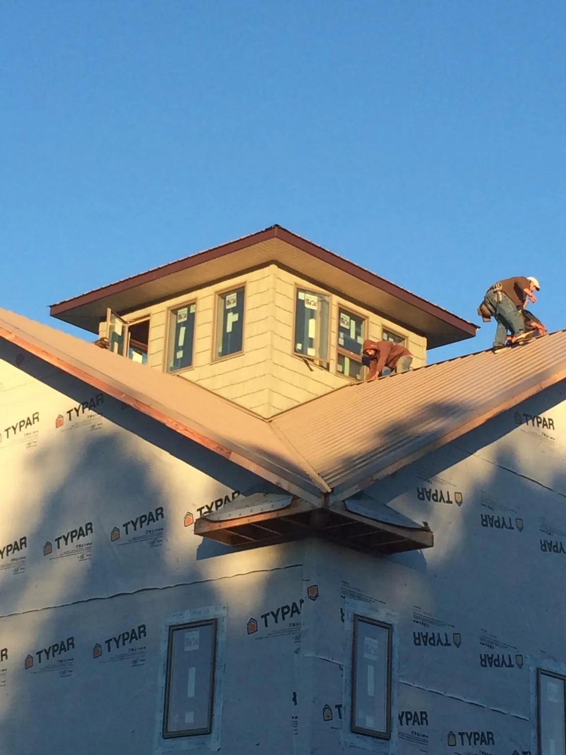Roofers working around a rooftop cupola on a new metal roof at sunset — Roof Waterproofing in Grahamsville by Roofing Brothers